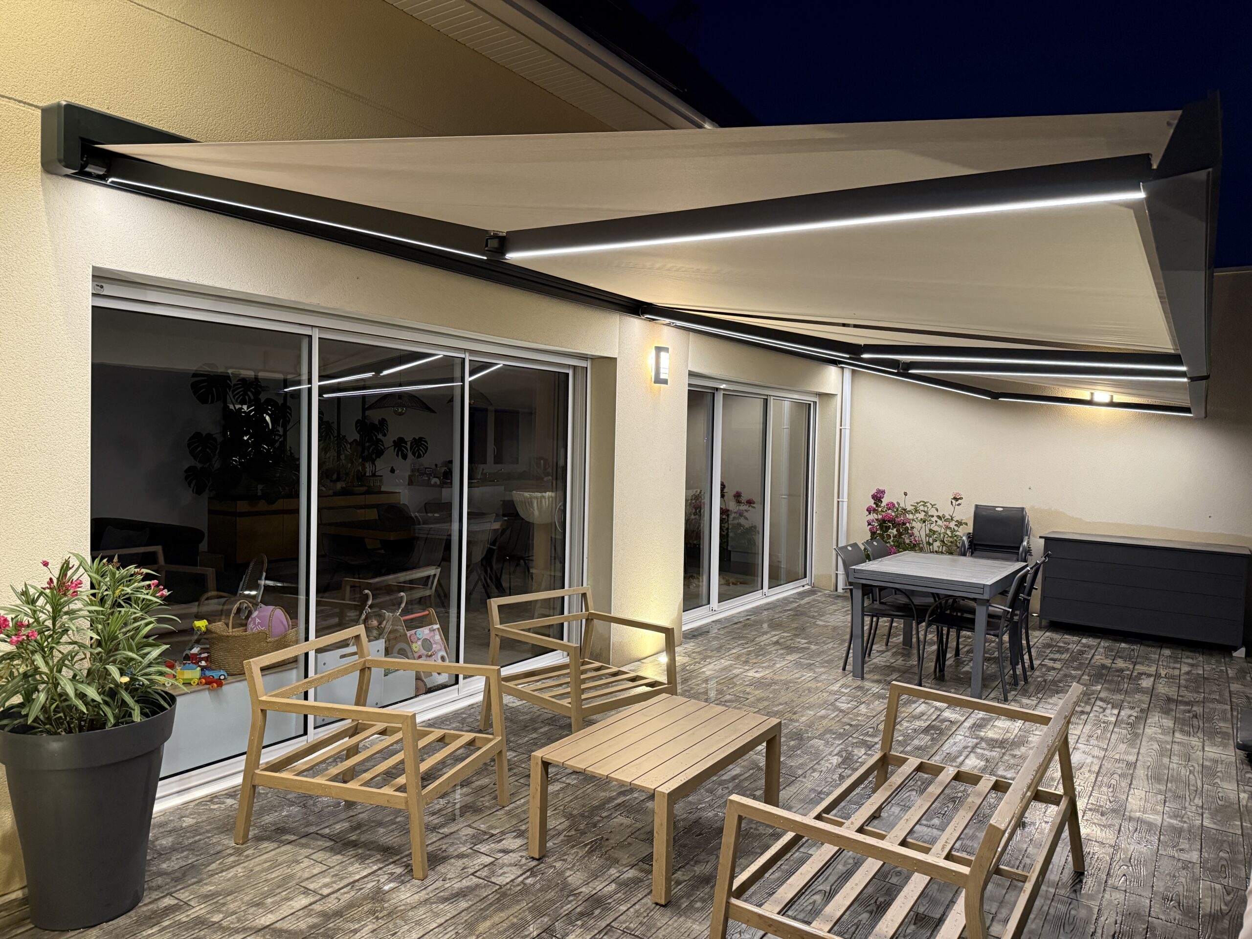 Terrasse moderne avec mobilier en bois et store déployé.