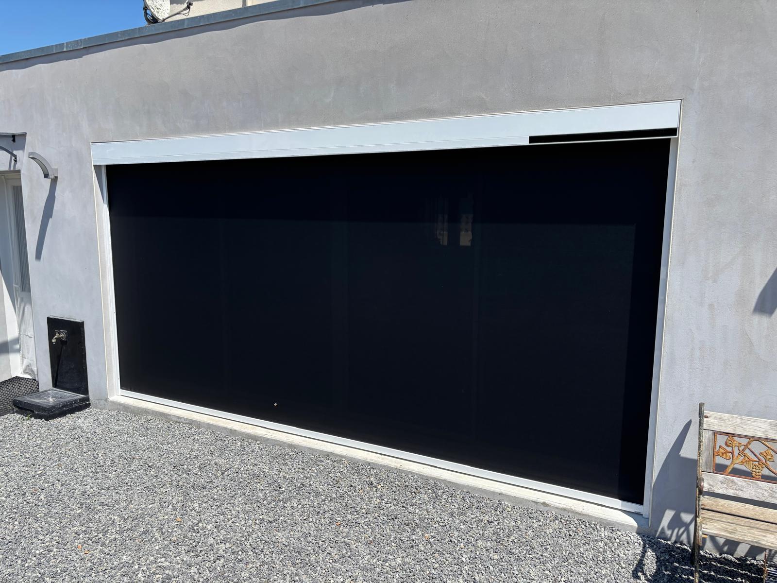 Grande porte de garage automatique en métal gris.