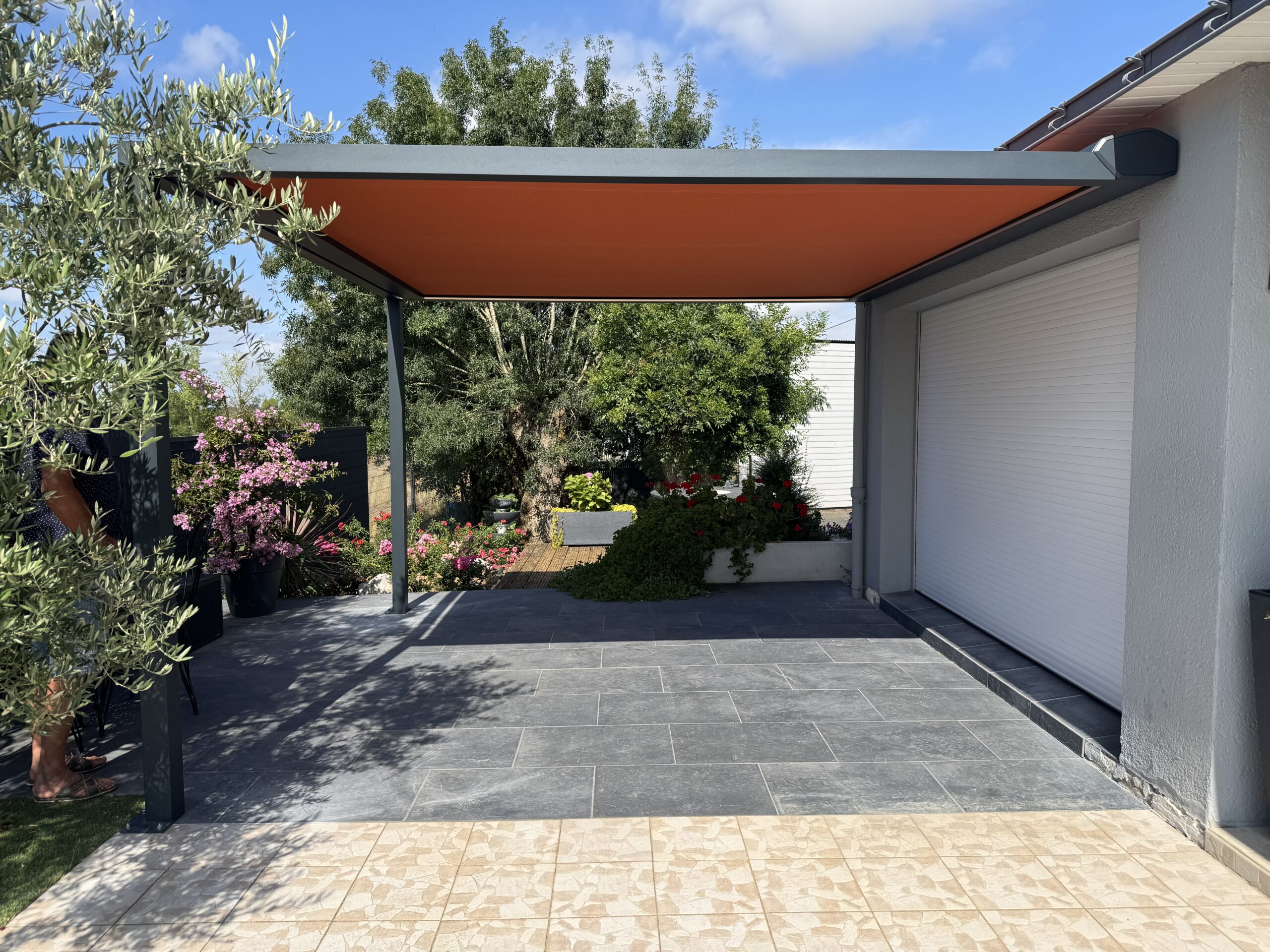Terrasse moderne avec pergola orange et jardin fleuri.
